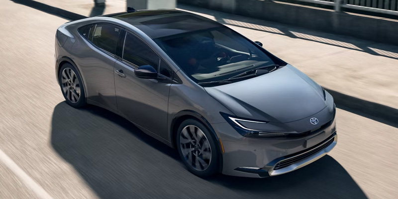 An all-new silver 2025 Toyota Prius Plug-in Hybrid driving across a city bridge. - Phil Meador Toyota Pocatello, ID