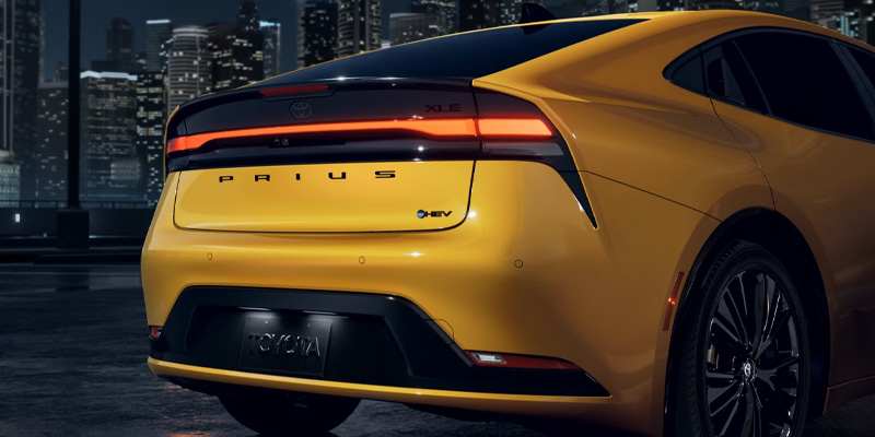 An all-new yellow 2025 Toyota Prius from the rear end with a city skyline backdrop. - Phil Meador Toyota Pocatello, ID