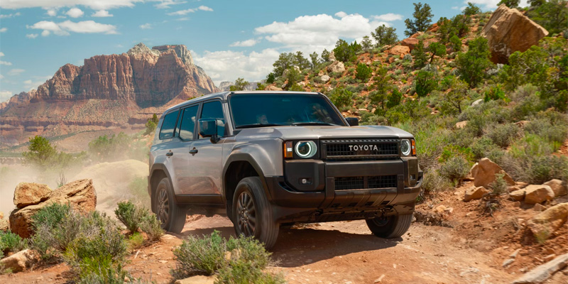 An all-new silver 2025 Toyota Land Cruiser driving through the mountainous desert. - Phil Meador Toyota Pocatello, ID