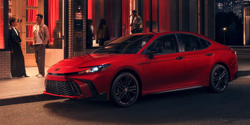 A red Toyota Camry parked in front of a restaurant